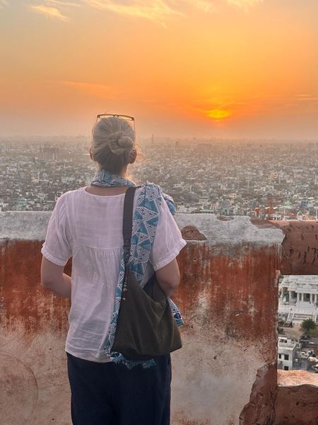 Guest admiring a golden sunset over Jaipur from a hilltop fort