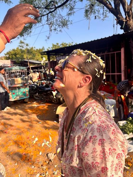 Guest receiving a traditional flower petal blessing at a Rajasthan market